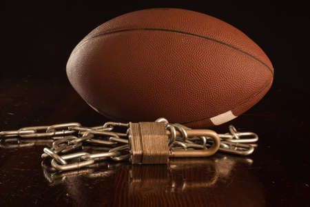 A close up of a football with a lock and chain in the foreground.の写真素材