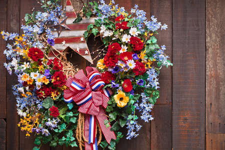 A close up of an Fouth of July wreath haning on a wood fence.の写真素材