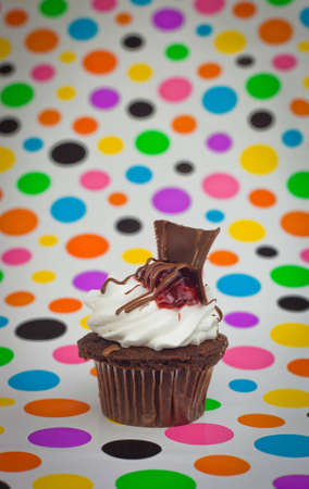 A close up of a dark chocolate cupcake with a polkadot background.の写真素材