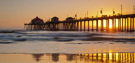 A wide shot of the Huntington Beach Pier during a bright orange sunset.の写真素材