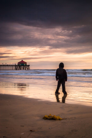 a young boy looking out to a sunset in Huntington Beach の写真素材