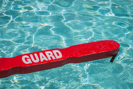 A close up shot of a life guards red rescue tube floating in a pool の写真素材