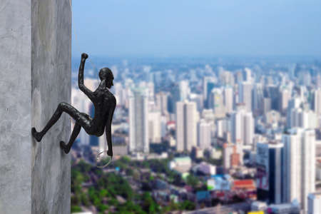 abstract background, clay doll climbing the wall and looking over to the cityの写真素材