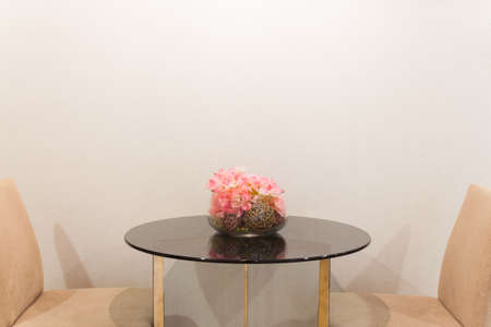 Artificial flower in glass vase on the table, soft cream color backgroundの写真素材