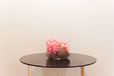 Artificial flower in glass vase on the table, soft cream color backgroundの写真素材