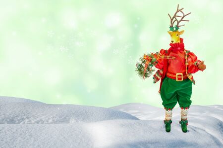Reindeer santa claus doll standing on snow hill with green blurred bokeh background.