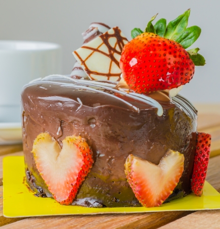 Chocolate cake with strawberry on top & tea white cup on the wood tableの写真素材