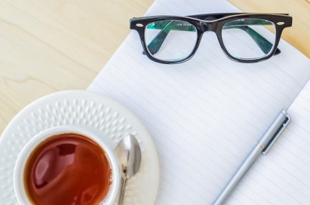 Paper note with eye glasses&white cupteaの写真素材