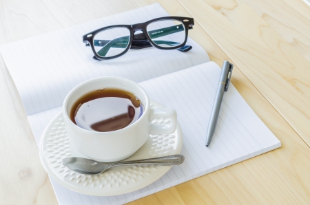 Paper note with eye glasses and white cup of teaの写真素材