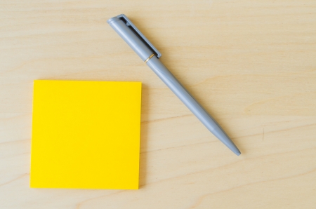 Yellow paper note with pen on the wood tableの写真素材