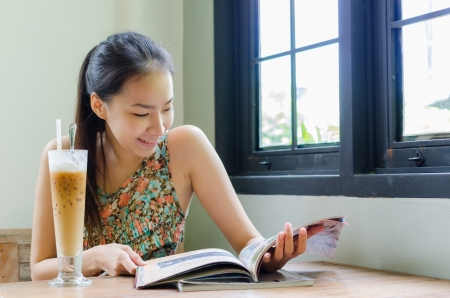 Girl reading a book with ice coffeeの写真素材