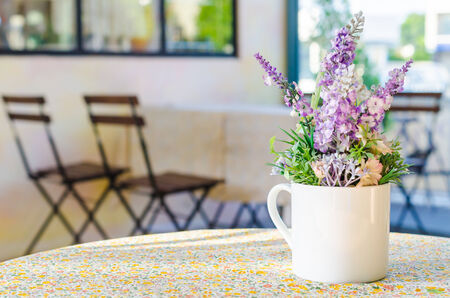 fake flowers in white cup vase on the table in coffee shop