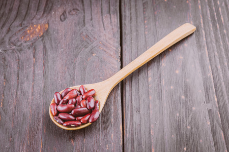 Red beans in wooden spoon on wooden backgroundの写真素材