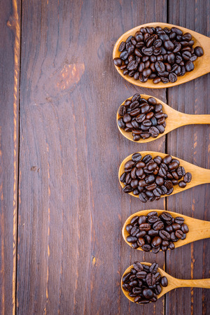 Coffee beans in wooden spoon on wood background - vintage effect style picturesの写真素材
