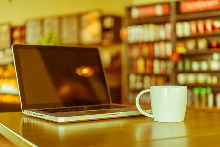 Coffee cup , laptop in coffee shop - vintage effect style picturesの写真素材