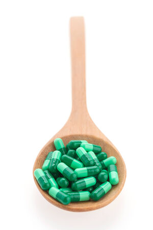 Pills drug on wooden spoon isolated on white backgroundの写真素材