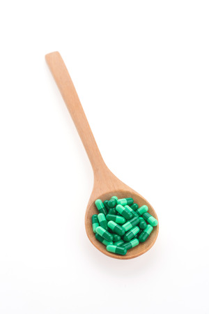 Pills drug on wooden spoon isolated on white backgroundの写真素材