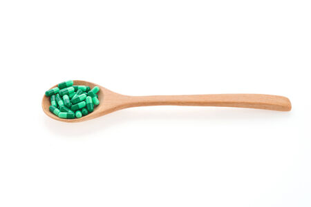 Pills drug on wooden spoon isolated on white backgroundの写真素材