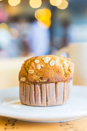 Muffin in white plate on wooden table in coffee shop cafeの写真素材