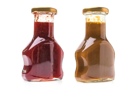 Caramel sauce and strawberry jam bottles isolated on white backgroundの写真素材