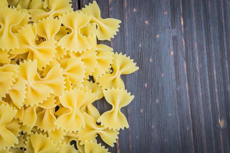 Raw pasta on wooden background - process old dark style picture