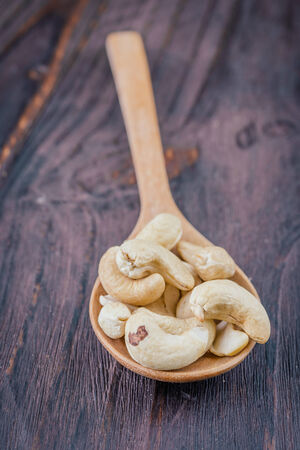 Cashew on spoon on wooden background - vintage effect style picturesの写真素材