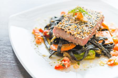 Grilled Tuna fish meat steak with black spaghetti - soft focus pointの写真素材