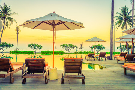 Twilight time Sunset umbrella deck chair pool - vintage filter effectの写真素材
