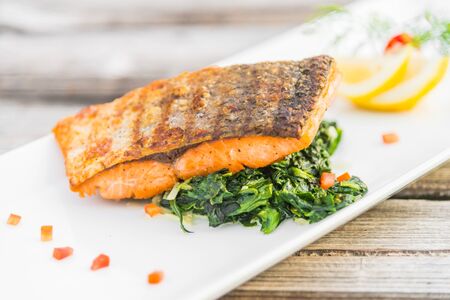 Grilled salmon fillet fish steak with lemon on white plate