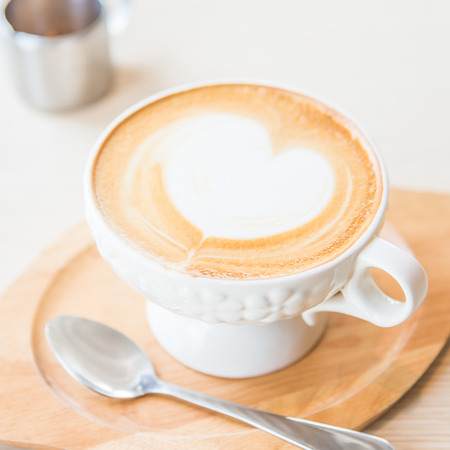 Hot latte coffee cup on wooden table in coffee shopの写真素材