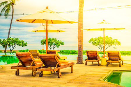 Umbrella chair in hotel pool resort with sunset - Vintage filter and sunflare light filter processingの写真素材