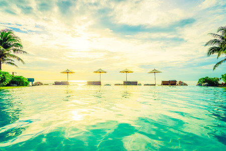 Umbrella and chair with sunset times at hotel pool resort - Vintage filter effect and dark processing style picturesのeditorial素材