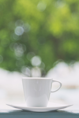 White coffee cup with outdoor view background - vintage filter effectの写真素材