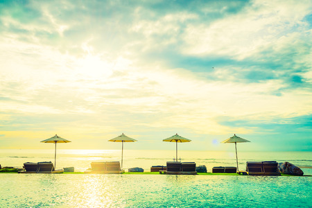 Umbrella and chair with sunset times at hotel pool resort - Vintage filter effect and dark processing style picturesのeditorial素材