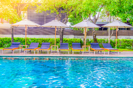 Outdoor Swimming pool and umbrella with chair deck in hotel resort for summer vacation background - sunflare filter effectのeditorial素材