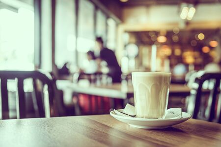Hot latte coffee glass in coffee shop cafe interior - vintage filterの写真素材