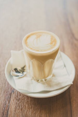 Hot latte coffee glass in coffee shop cafe interior - vintage filterの写真素材