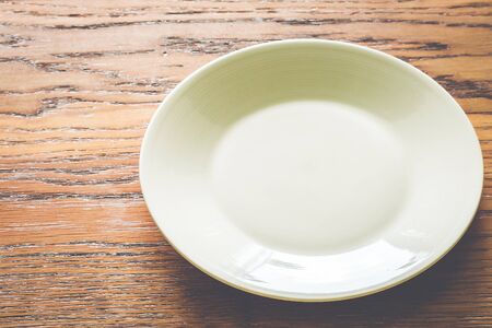 Empty white plate on wood background - vintage filter