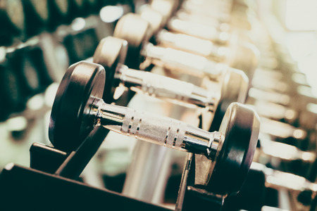 Selective focus point on Dumbbell in fitness and gym room interior - Vintage filter effect