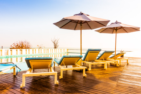Beautiful luxury swimming pool in hotel resort with umbrella and chair in sunset times - Vintage Filter and Boost up color processingの写真素材