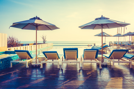 Beautiful luxury swimming pool in hotel resort with umbrella and chair in sunset times - Vintage Filter and Boost up color processingの写真素材
