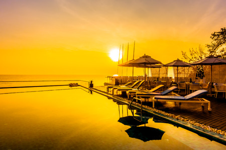 Beautiful luxury swimming pool in hotel resort with silhouette umbrella and chair around pool with sunset and twilight times - Vintage Filter and Boost up color Processingのeditorial素材