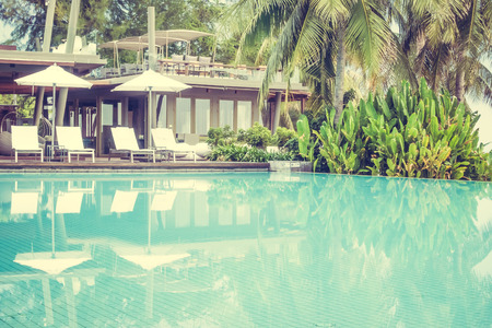 Beautiful luxury swimming pool in hotel pool resort with umbrella beach and chair - Vintage Filter...