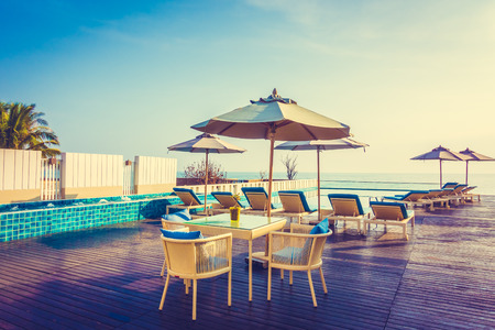 Beautiful luxury swimming pool in hotel resort with umbrella and chair in sunset times - Vintage Filter and Boost up color processingのeditorial素材