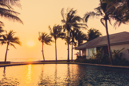 Silhouette palm tree on the beach and sea around beautiful luxury swimming pool in sunset - Vintage Filter and Boost up color Processingの写真素材