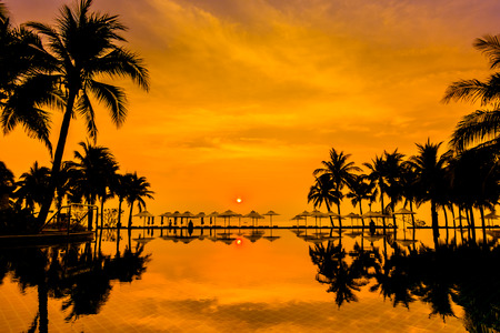 Silhouette palm tree with umbrella and chair around beautiful luxury swimming pool in hotel resort at Sunset time - Vintage Filter and Boost up Color Processingのeditorial素材
