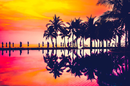 Silhouette palm tree with umbrella and chair around beautiful luxury swimming pool in hotel resort at Sunset time - Vintage Filter and Boost up Color Processingのeditorial素材