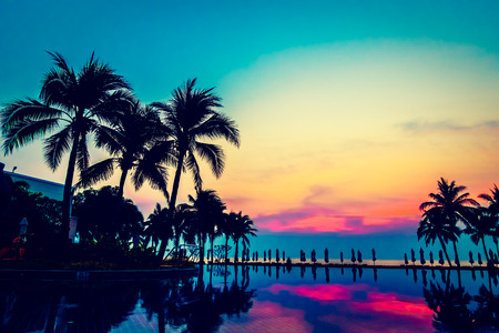 Silhouette palm tree with umbrella and chair around beautiful luxury swimming pool in hotel resort at Sunset time - Vintage Filter and Boost up Color Processingのeditorial素材