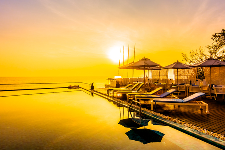 Beautiful luxury swimming pool in hotel resort with silhouette umbrella and chair around pool with sunset and twilight times - Vintage Filter and Boost up color Processingのeditorial素材