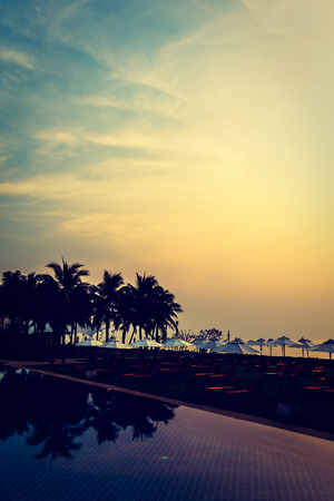 Silhouette palm tree with umbrella and chair around beautiful luxury swimming pool in hotel resort at Sunset time - Vintage Filter and Boost up Color Processingのeditorial素材